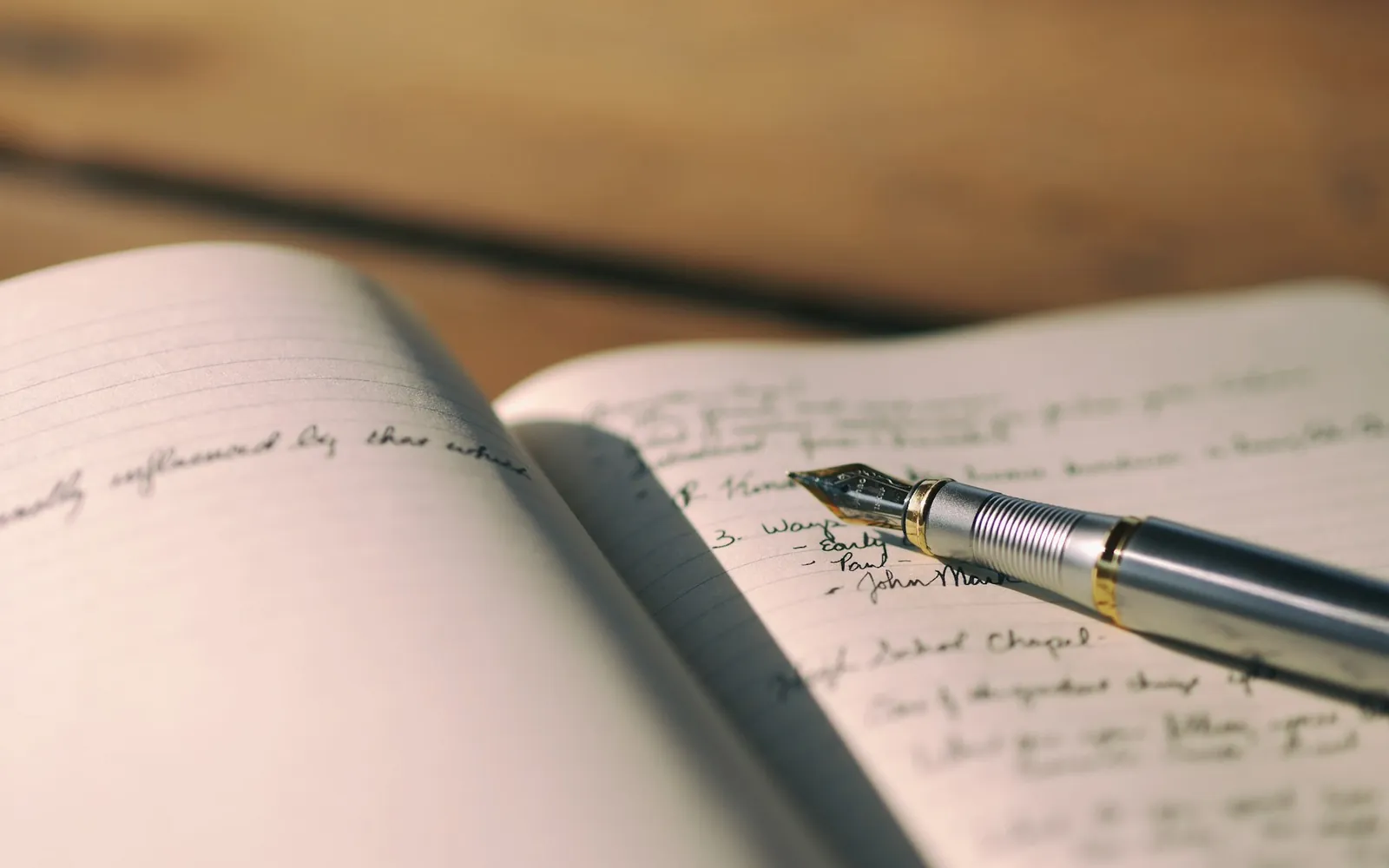Un stylo plume posé sur un carnet manuscrit ouvert